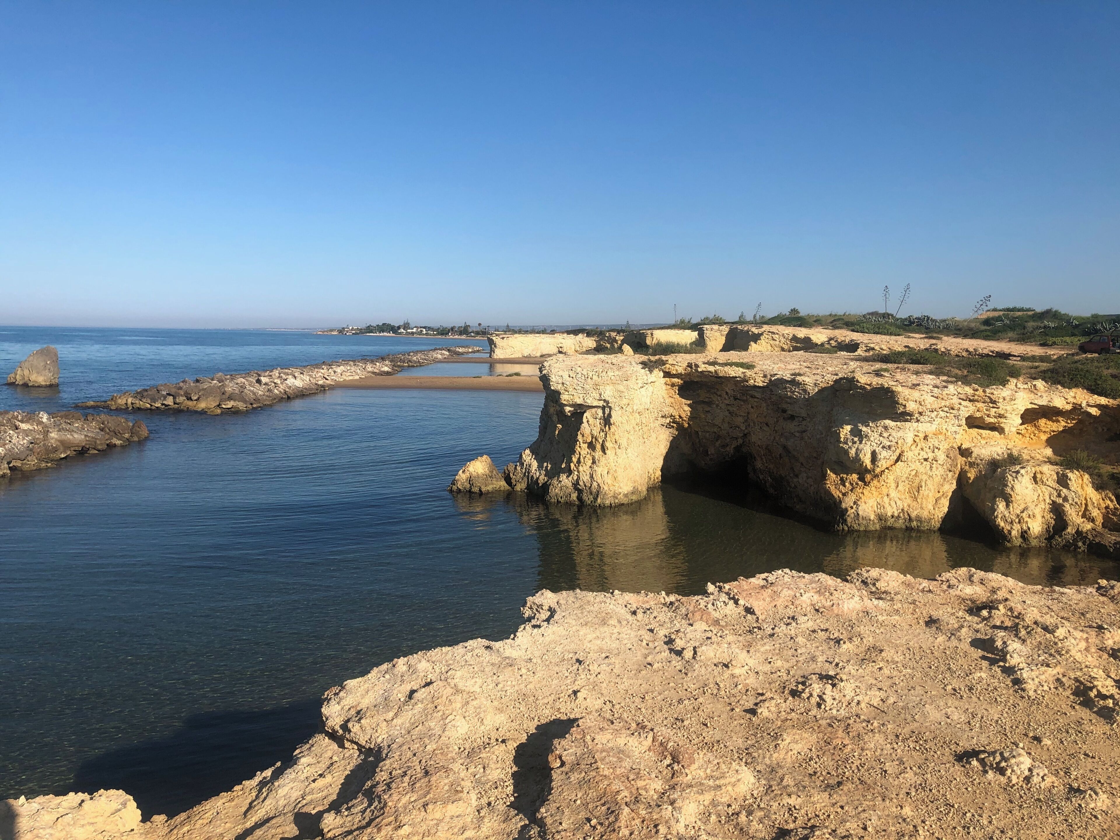 A coastal landscape with rocky formations and calm waters.