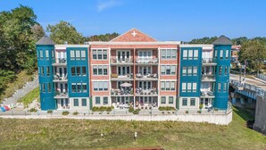 A multi-story building with balconies, a central courtyard, and a waterfront view. - 2 Bedroom Downtown Waterfront Condo (Manistee)
