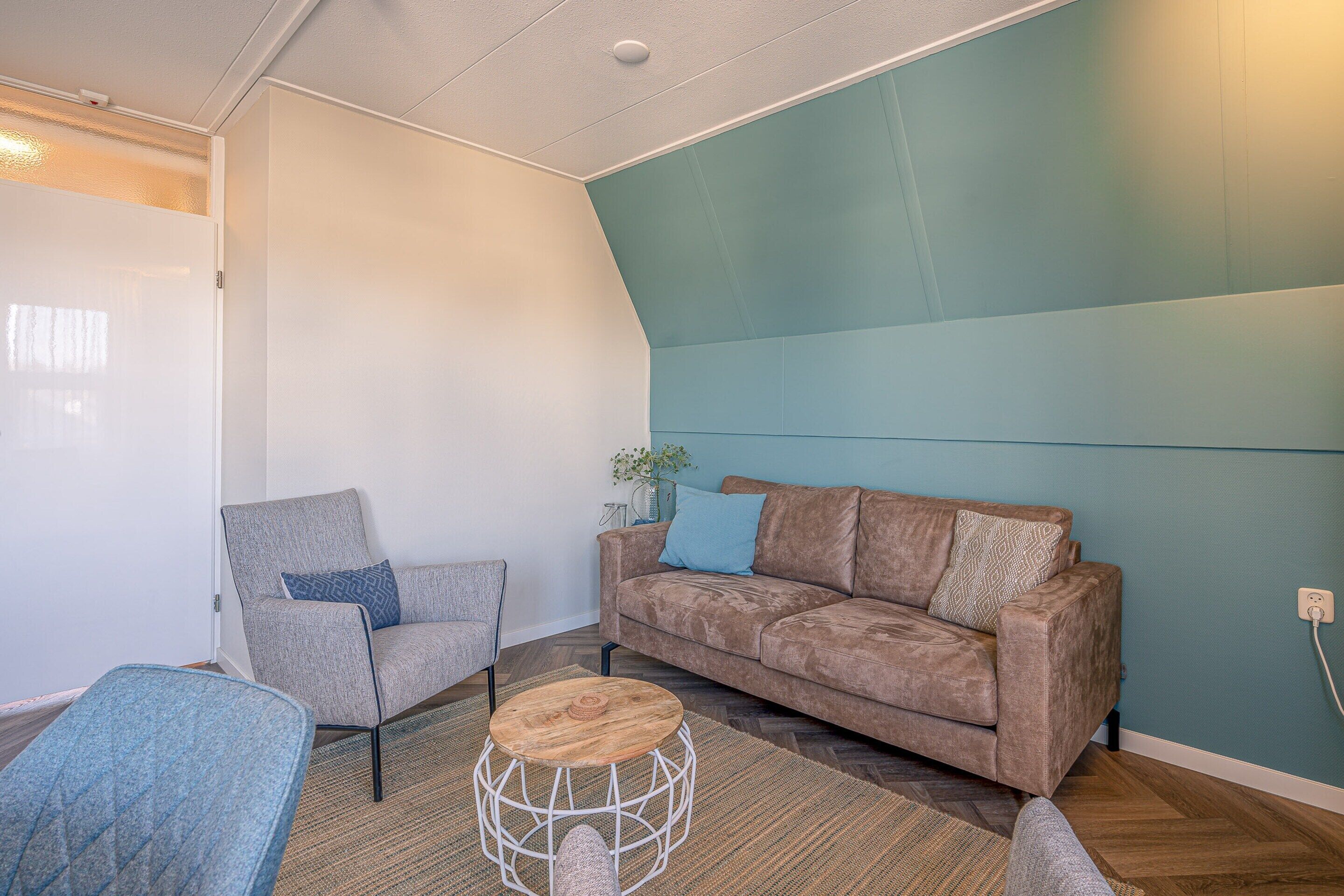A modern living room with a sofa, armchair, and round coffee table.
