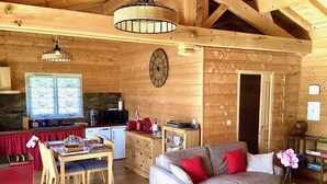 A cozy wooden cabin interior with a dining area, kitchenette, and living room. - XIMISTA - BARDOS - Gîte (BARDOS)