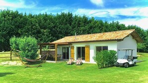 A small house with a tiled roof, a covered patio, and a golf cart parked outside. - XIMISTA - BARDOS - Gîte (BARDOS)