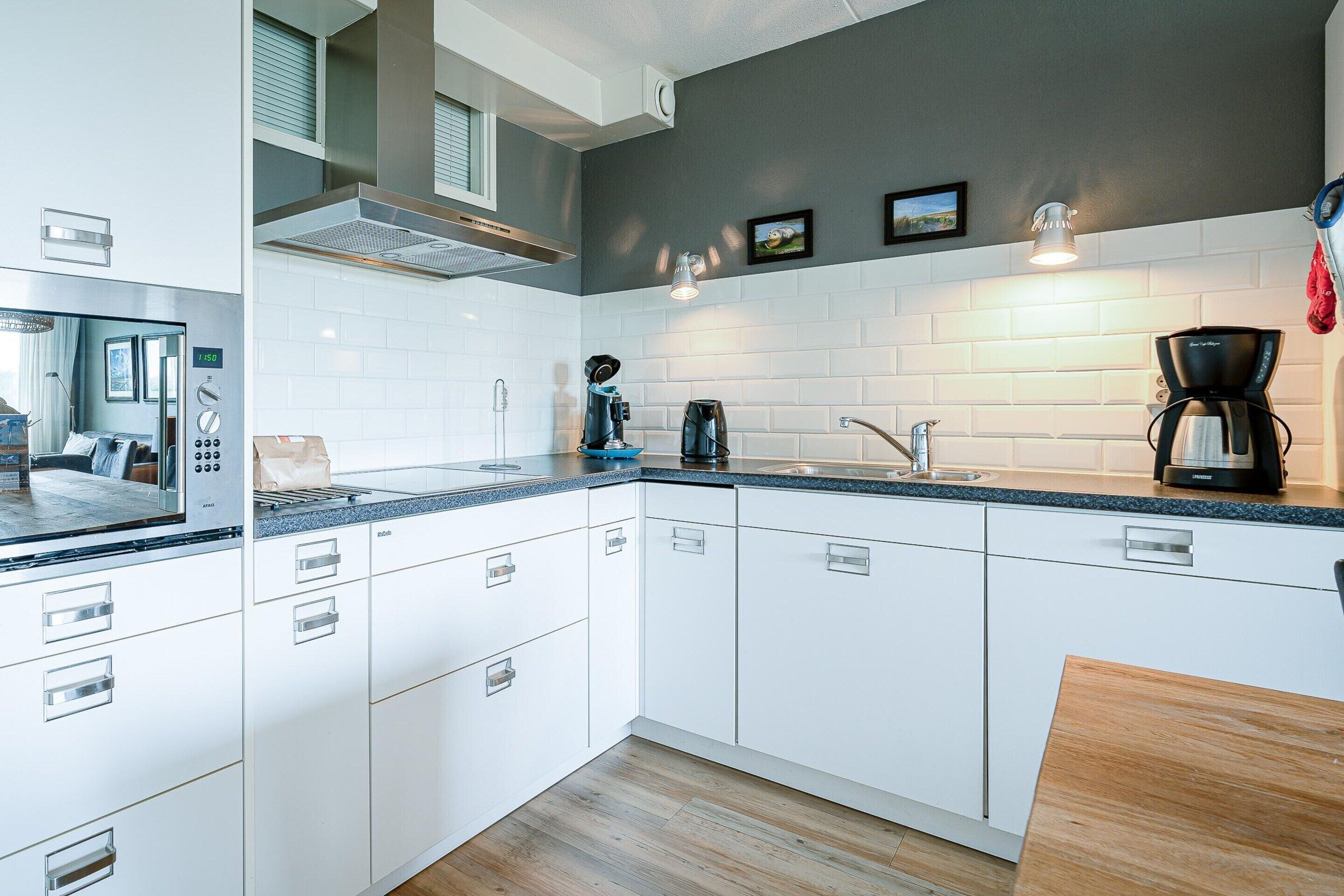 A modern kitchen with white cabinets, a built-in microwave, and a coffee maker.