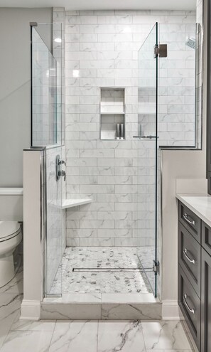 Ein modernes Badezimmer mit einer Duschkabine aus Glas, Marmorfliesen und einem minimalistischen Design.