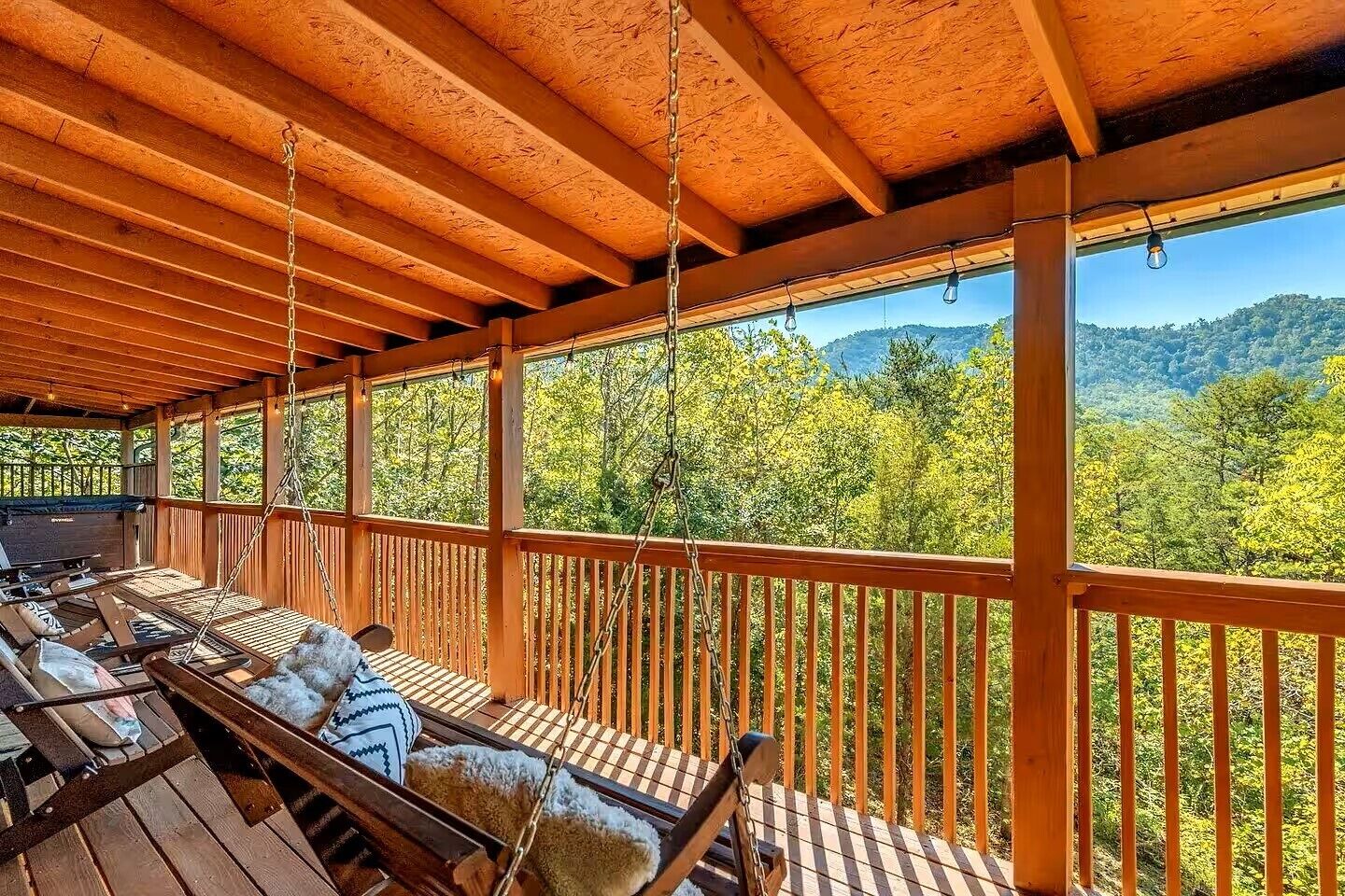 Eine überdachte Terrasse mit Holzwerteln und Blick auf einen bewaldeten Gebirgszug.