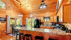 A wooden cabin interior with a kitchen, dining area, and bar. - New Listing! Mountain Views! 3B/3Ba Sleep 6-7, Hot Tub, Close to Everything! (Sevierville)