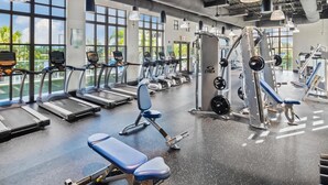 Un gimnasio con cintas de correr, máquinas de pesas y bancos.
