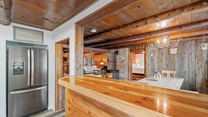 Una cocina con una isla de madera, un refrigerador de acero inoxidable y una pared de ladrillo.