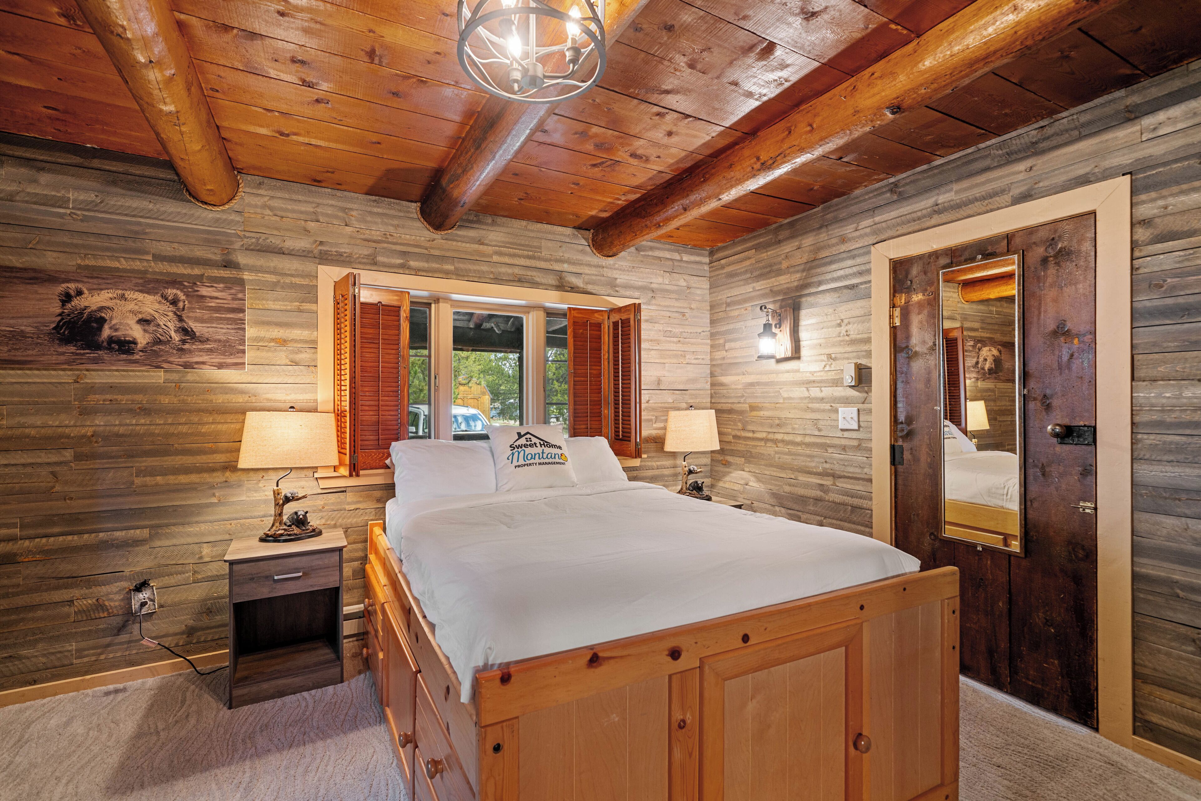 A wooden cabin bedroom with a bed, nightstands, and a mirror.