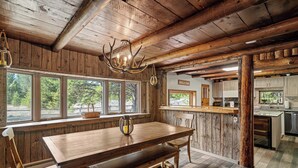 Un interior rústico de madera con una gran mesa de comedor, vigas de madera y una araña.