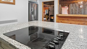 Una cocina con encimera de granito, electrodomésticos de acero inoxidable e interior de madera.