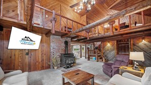 Amplia sala de estar con chimenea, muebles de madera y un altillo con balcón.