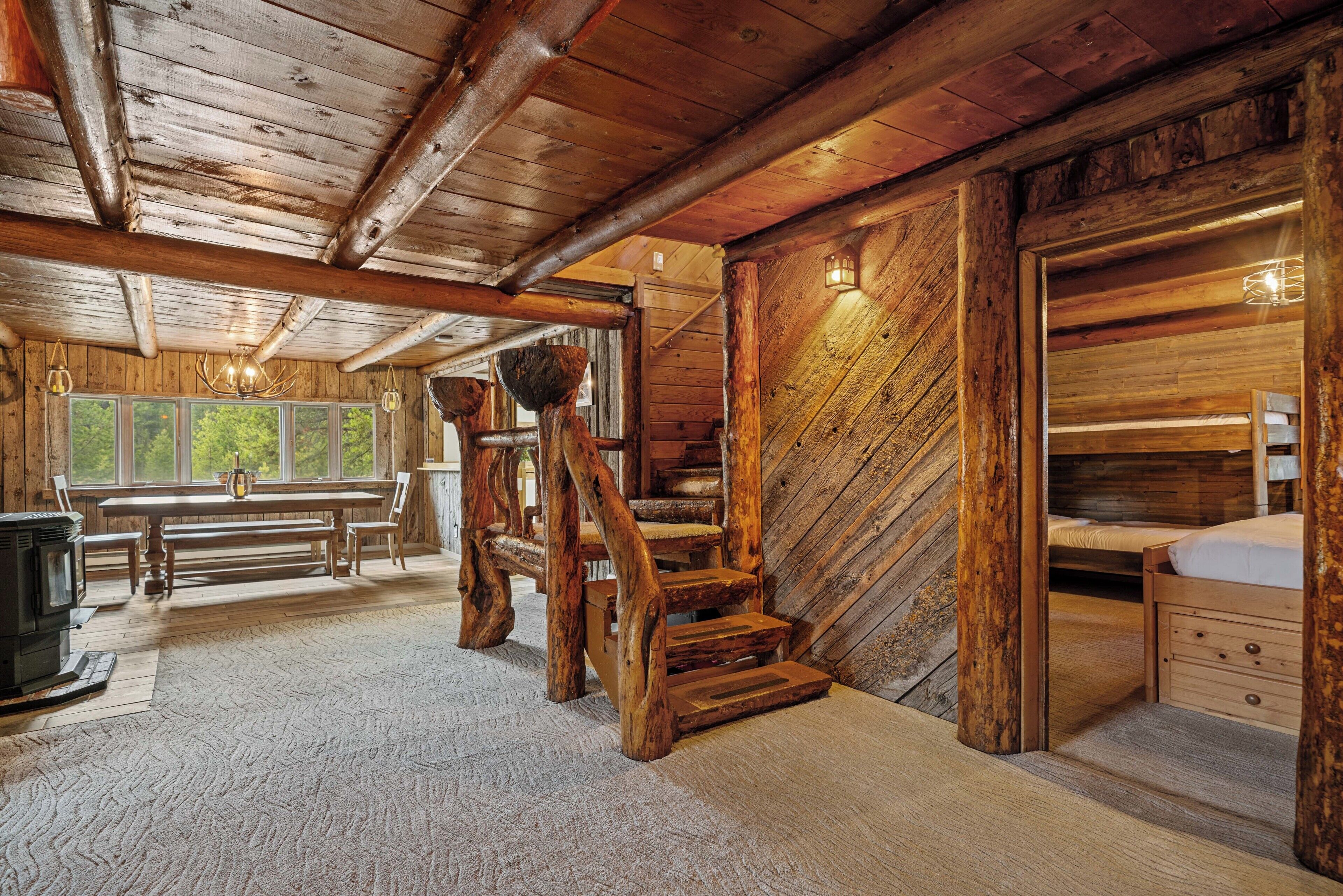 L’intérieur d’un chalet rustique, avec un escalier en bois, un coin repas et une chambre à coucher accueillante.