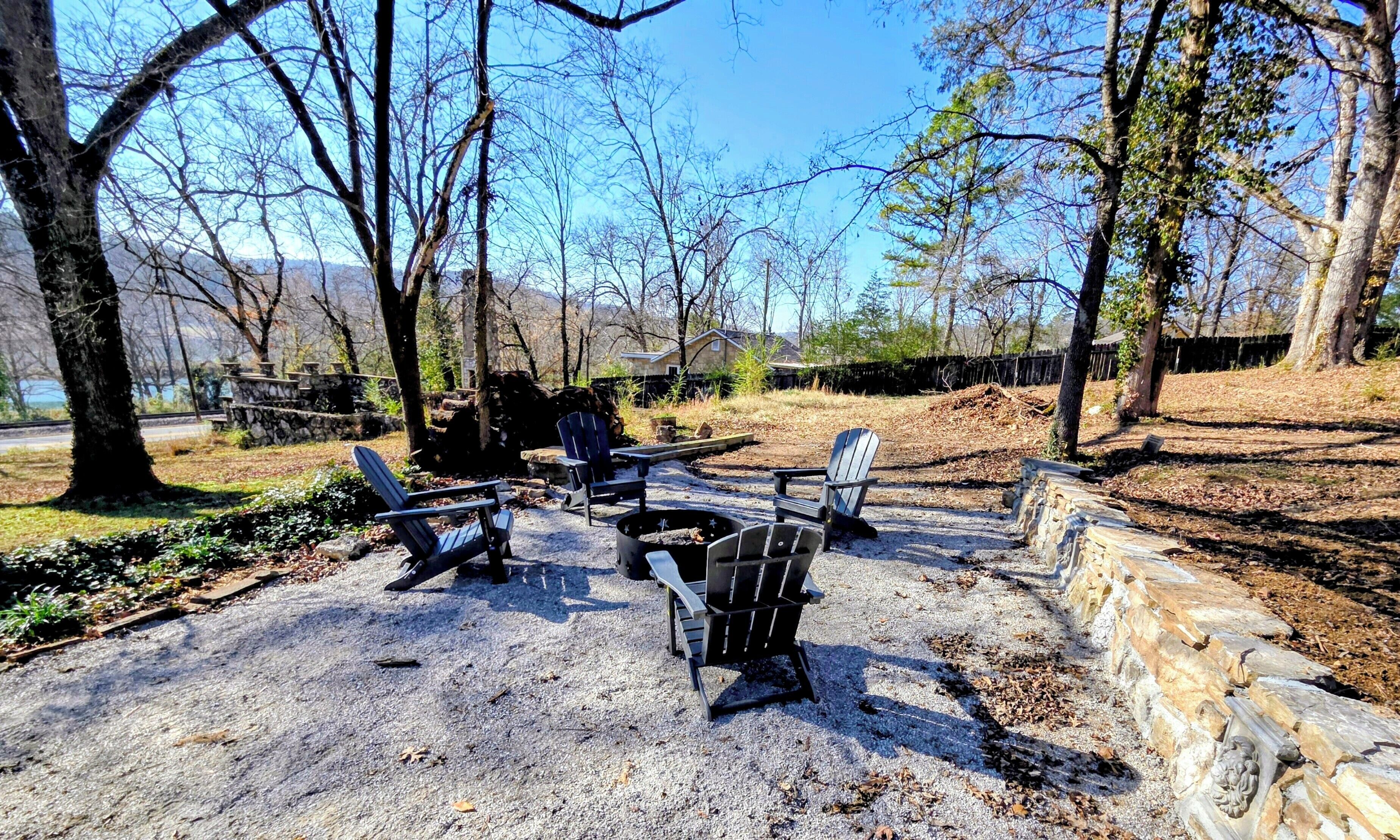 A gravel patio with Adirondack chairs and a fire pit.