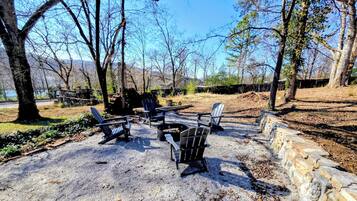 A gravel patio with Adirondack chairs and a fire pit.