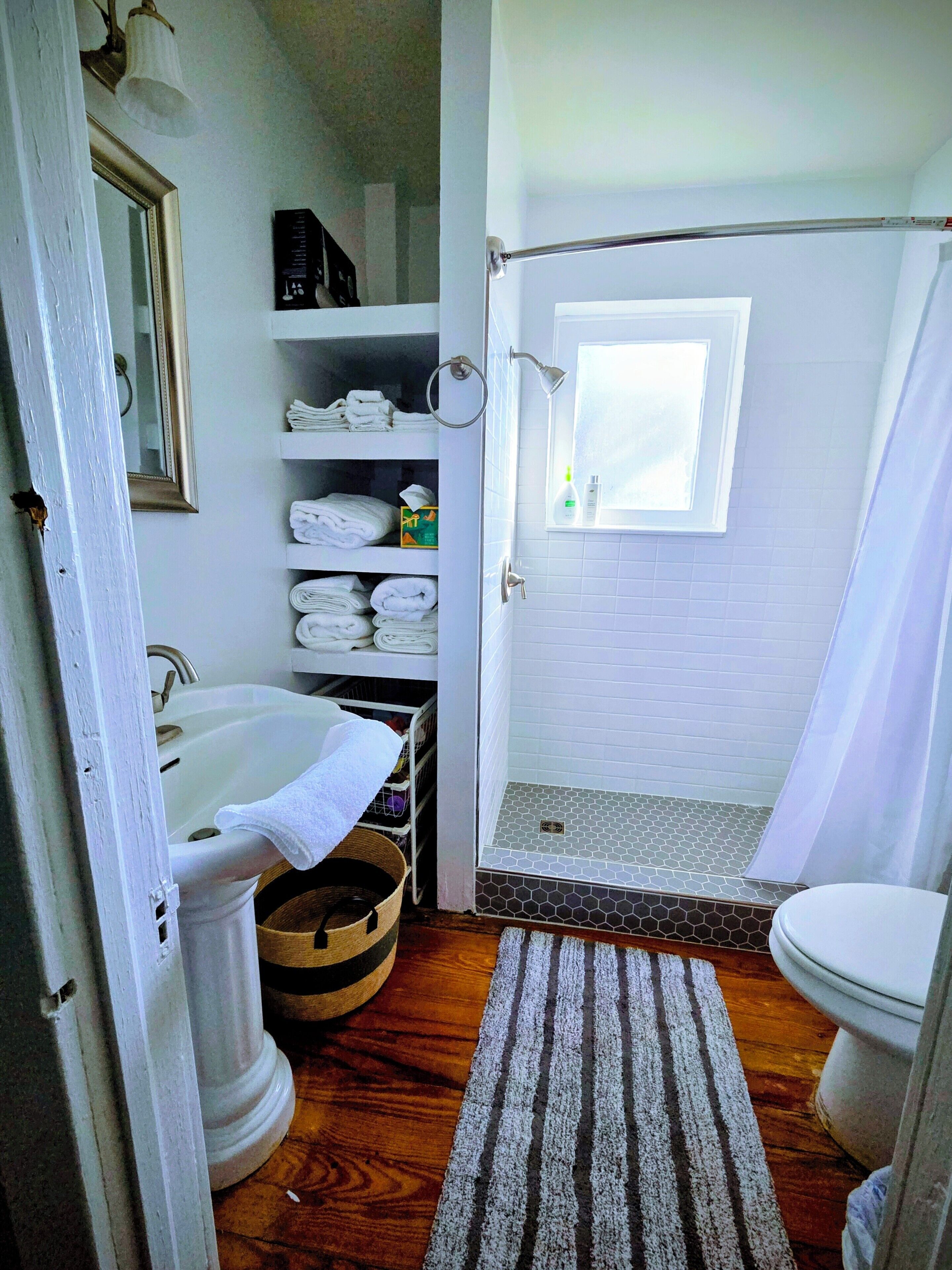 A bathroom with a shower, toilet, sink, and a towel rack.