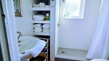 A bathroom with a shower, toilet, sink, and a towel rack.