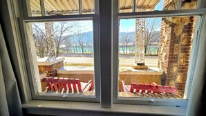 A window with a view of a brick building and a paved area with red barriers. - Historic Carrie Tucker Cottage with view of Spring River in charming Hardy, Ark. (Hardy)