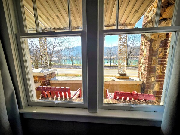 A window with a view of a brick building and a paved area with red barriers. - Historic Carrie Tucker Cottage with view of Spring River in charming Hardy, Ark. (Hardy)