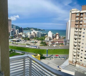 Um edifício alto com vários andares, estacionamento e vista para a paisagem costeira com edifícios e uma praia.