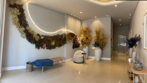Un intérieur moderne agrémenté d’un luminaire incurvé, d’un banc, d’une chaise et de grands pots de plantes.
