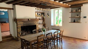 Un comedor con una mesa y sillas de madera, una chimenea de ladrillo y un ventanal con luz natural.