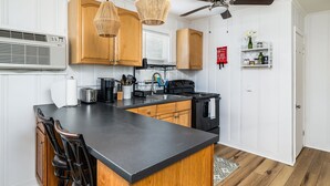 A kitchen with wooden cabinets, a black countertop, hanging wicker lights, a ceiling fan, and a built-in stove. - 2 Blocks to Beach | Downtown OC +  1 Parking Space (Ocean City)