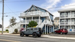 A two-story building with a balcony, a staircase, and a parked SUV. - 2 Blocks to Beach | Downtown OC +  1 Parking Space (Ocean City)
