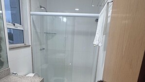 Un baño moderno con cabina de ducha de vidrio, un inodoro y un lavabo.