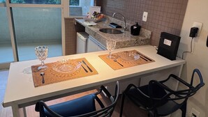 Una cocina moderna con encimera blanca, dos sillas negras y una mesa de comedor.