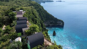A coastal property with multiple buildings, lush greenery, and a clear view of the sea.