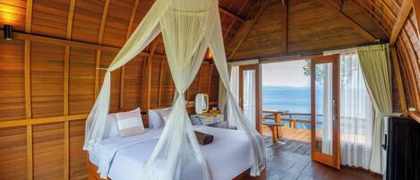 A wooden room with a bed, a nightstand, and a view of the ocean.