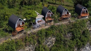 Un paisaje exuberante y aislado, con cuatro cabañas en forma de cúpula conectadas por un pasillo de madera.