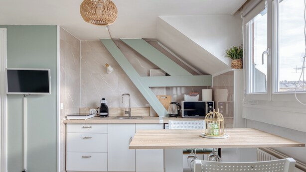 Une cuisine moderne dotée d’un plan de travail en bois, d’un four à micro-ondes encastré, d’une bouilloire et d’un luminaire suspendu.