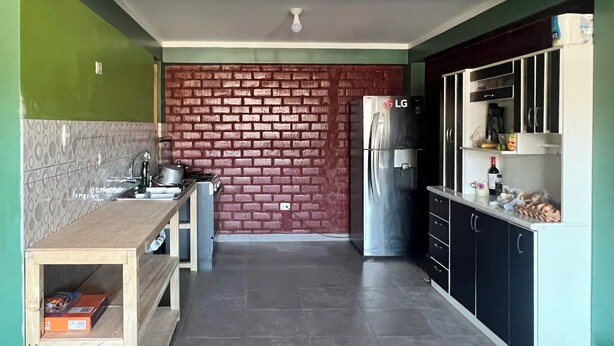 A compact kitchen with a brick wall, a stainless steel refrigerator, and a wooden countertop. - Affordable, convenient, and inviting stay in Huaraz. Perfect for groups! (Huaraz)