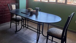 A dining area with a brick wall, a large window with a view of a hilly landscape, and a table with chairs. - Affordable, convenient, and inviting stay in Huaraz. Perfect for groups! (Huaraz)