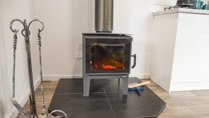 Una cucina moderna con un camino a legna, un tappetino nero sotto il camino e un piano di lavoro bianco.