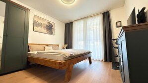 A bedroom with a wooden bed, a wardrobe, a painting, and a window with curtains. - Fabulous 1-bedroom apartment in Essen (Essen)