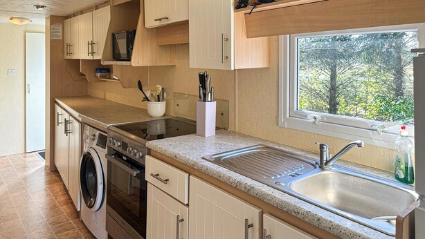 Een kleine keuken met een wasmachine, fornuis en spoelbak.