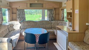 Een gezellig interieur van een camper, met een eethoek, bank en kitchenette.