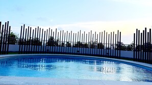 A swimming pool with a tiled deck and a metal fence. - Full Service Apartment in Cantonments, Accra. (Accra)