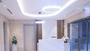 A modern reception area with a marble floor, a reception desk, a large potted plant, and a glass door leading outside. - Full Service Apartment in Cantonments, Accra. (Accra)