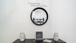 A black marble console table with a framed sign, two white ceramic busts, and a round mirror on a white wall. - Suléa Horizon Apartment (Menfi)