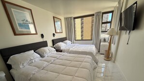 A hotel room with three beds, a TV, and a large window with curtains. - Ocean View Retreat•4 Mn Walk 2 Beach•Lanai•Sleep 6 @ Waikiki Banyan #908 Tower 1 (Honolulu)