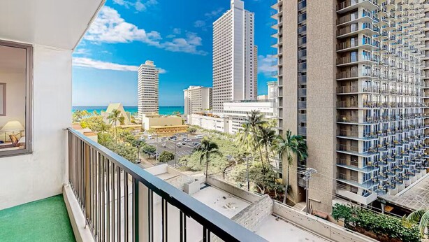 A high-rise hotel with multiple balconies, a view of the ocean, and surrounding urban buildings. - Ocean View Retreat•4 Mn Walk 2 Beach•Lanai•Sleep 6 @ Waikiki Banyan #908 Tower 1 (Honolulu)