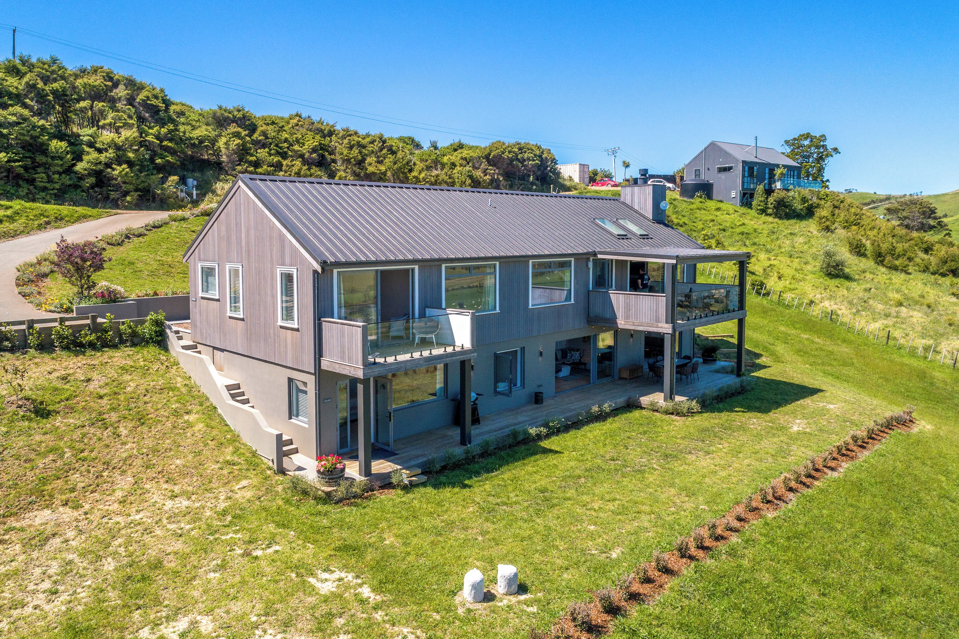 A modern two-story house with a large balcony, a covered porch, and a well-maintained lawn.