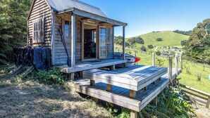 A wooden cabin with a porch and a view of a green landscape.