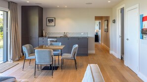 A modern kitchen with grey cabinets, a central island, and a dining area with a table and chairs.