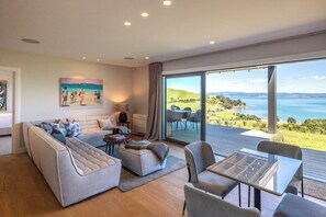 Una sala de estar moderna con un sofá grande, una mesa de centro de vidrio y vista al mar.