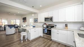 A modern kitchen with white cabinets, stainless steel appliances, and a granite countertop. - Resort style community, heated pools, club house, game room, 15 mins to beaches. (Arundel)