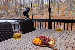 Une table en bois, un verre de vin blanc, une bouteille de vin blanc et une planche de fromages accompagnée de raisins et de différents fromages.